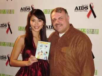 Miss Universe Riyo Mori holding up a copy of the DVD for the 'How Do I Look' documentary, pictured with the filmmaker and activist Wolfgang Busch on World AIDS Day 2007.